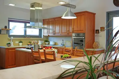 a kitchen with wooden cabinets and a table with chairs at Villa Sea Horizon in Protaras