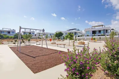 a park with a swing and flowers and buildings at Villa Daniella in Protaras