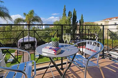 a table and chairs on a balcony with a glass of wine at Villa Crystalia - 350m from Kalamies Beach in Protaras