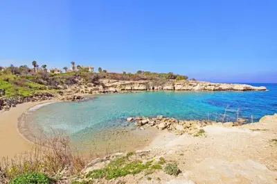 a beach with blue water and a rocky island at Villa Crystalia - 350m from Kalamies Beach in Protaras
