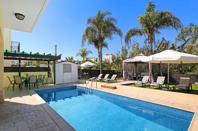 a swimming pool with chairs and umbrellas in a house at Villa Crystalia - 350m from Kalamies Beach in Protaras