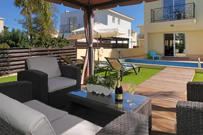 a patio with chairs and a table with a umbrella at Villa Crystalia - 350m from Kalamies Beach in Protaras