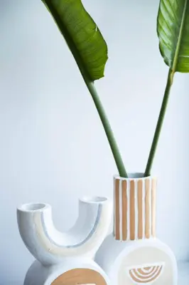a white vase with a green plant in it at Villa Orchard by Tangerine in Protaras