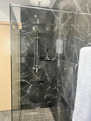 a bathroom with a shower with a black marble wall at Oceania bay village Pyla in Larnaka
