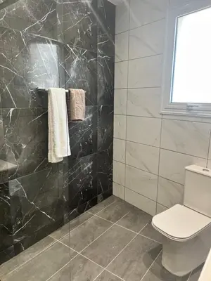 a bathroom with a toilet and a black marble wall at Oceania bay village Pyla in Larnaka