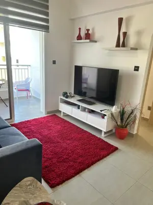 a living room with a television and a red rug at Oceania bay village Pyla in Larnaka