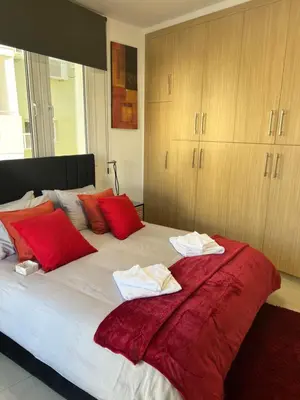 a bedroom with a large bed with red pillows at Oceania bay village Pyla in Larnaka