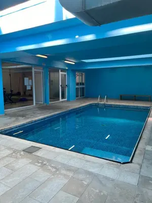 a large swimming pool in a building with blue walls at Oceania bay village Pyla in Larnaka