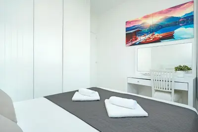 a white bedroom with a bed and a desk at Villa Indigo in Protaras