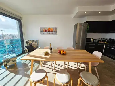 a kitchen and dining room with a wooden table and chairs at Dios Ponte Finikoudes Beachfront in Larnaka