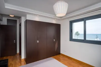 a bedroom with wooden cabinets and a window with the ocean at Dios Ponte Finikoudes Beachfront in Larnaka