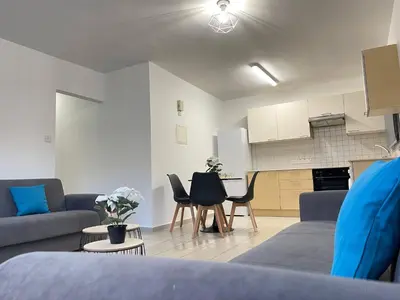a living room with a couch and a table and chairs at Aurora Holiday Apartment - Ayia Napa in Ayia Napa