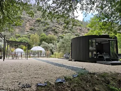 a black house on a gravel road with a table and a tent at River Glamping Kalopanayiotis in Kalopanayiotis