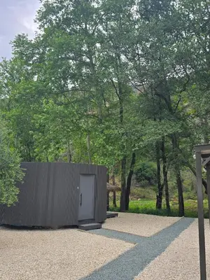 a small building with a white door next to trees at River Glamping Kalopanayiotis in Kalopanayiotis