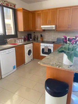 a kitchen with wooden cabinets and a counter with purple flowers at Villa Ocean Breeze in Paralimni