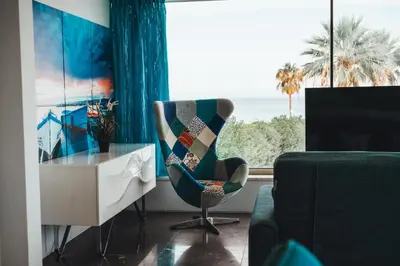 a living room with a chair and a desk and a window at Protaras Beachfront Thalassa Suite in Protaras