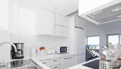 a white kitchen with white cabinets and a sink at Protaras Beachfront Thalassa Suite in Protaras