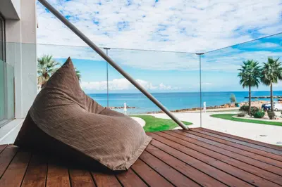 a hammock on a deck with a view of the ocean at Protaras Beachfront Thalassa Suite in Protaras