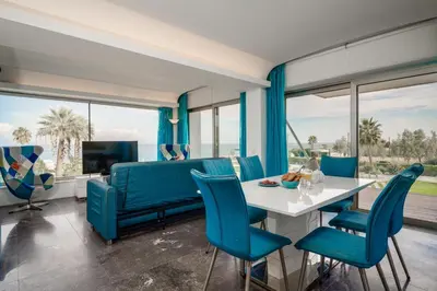 a living room with a table and blue chairs at Protaras Beachfront Thalassa Suite in Protaras