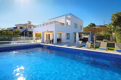 a villa with a swimming pool in front of a house at Cape Panorama Villa in Protaras
