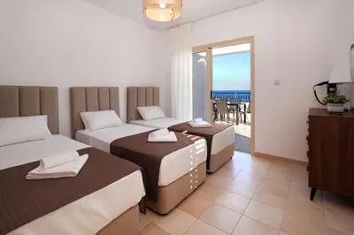 a hotel room with three beds and a balcony at Cape Panorama Villa in Protaras