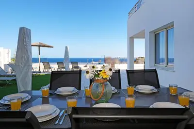 a table with plates and a vase with flowers on it at Cape Panorama Villa in Protaras