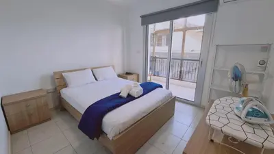 a bedroom with a bed and a balcony with a fan at STAY Finikoudes Soul in Larnaka