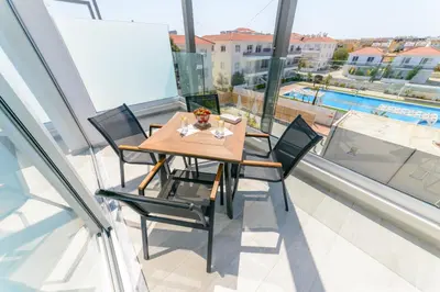 a table and chairs on a balcony with a pool at Apartament De Lux MS 1 - C in Paralimni