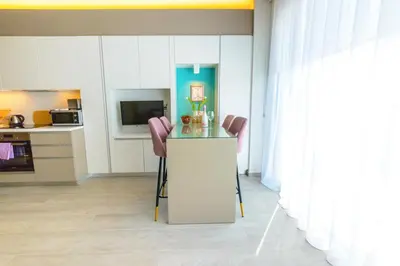 a kitchen with a counter and two pink chairs at Apartament De Lux MS 1 - C in Paralimni