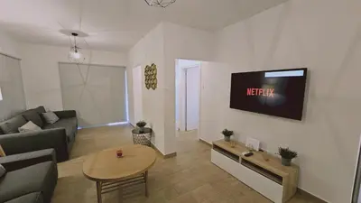 a living room with a couch and a tv on a wall at STAY Sky Apartment in Limassol