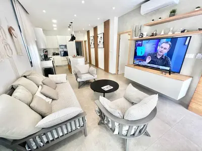 a living room with white furniture and a large screen tv at Crystal-Blue-Villa Protaras in Protaras
