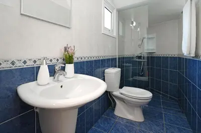 a blue tiled bathroom with a sink and a toilet at Villa Posidonia - 200m from Sandy Beach in Ayia Napa