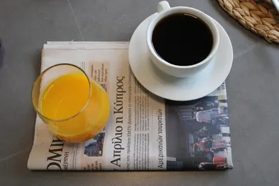 a newspaper with a glass of orange juice and a cup of coffee at Hypnos Residence in Nicosia