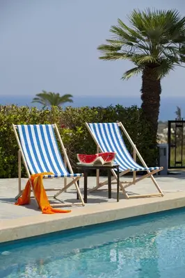 two chairs and a table next to a swimming pool at Ayios Elias Pearl in Protaras