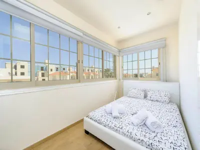 a bedroom with a bed with two pillows and windows at Theodora in Protaras