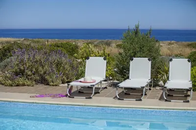 two chairs and a table next to a swimming pool at Protaras Seafront Villa Melissa in Protaras