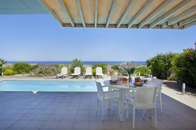 a patio with a table and chairs and a pool at Protaras Seafront Villa Melissa in Protaras