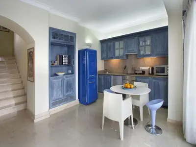 a kitchen with blue cabinets and a white table and chairs at Protaras Nausicaa Villa Mykonos in Protaras