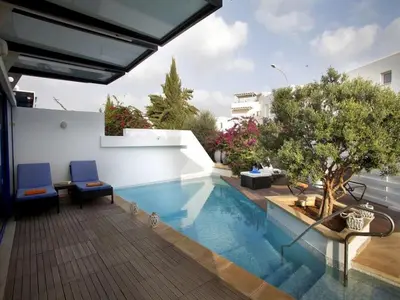 a swimming pool with two blue chairs next to a building at Protaras Nausicaa Villa Mykonos in Protaras