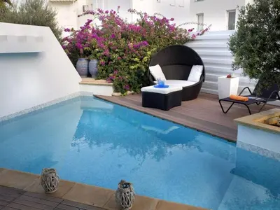 a small swimming pool with a chair and a table at Protaras Nausicaa Villa Mykonos in Protaras