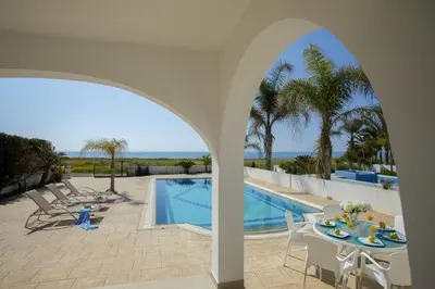 a patio with a table and chairs next to a swimming pool at Ayia Thekla Sea Front in Ayia Napa