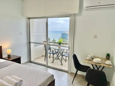 a bedroom with a bed and a table with chairs at Enaerios SeaView Studio in Limassol