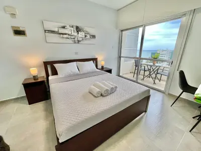 a bedroom with a large bed with a balcony at Enaerios SeaView Studio in Limassol