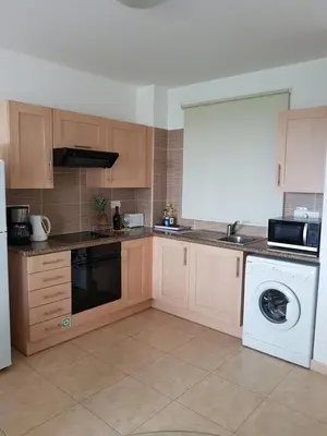 a kitchen with wooden cabinets and a washer and dryer at Holiday Apartment with Sea View (0002913) in Paralimni