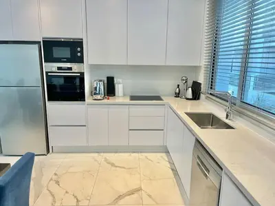 a kitchen with white cabinets and a stainless steel refrigerator at Sol e Mar Villa 2 in Paralimni
