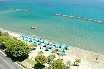 an aerial view of a beach with blue umbrellas and chairs at Eden Dream Apartments in Limassol