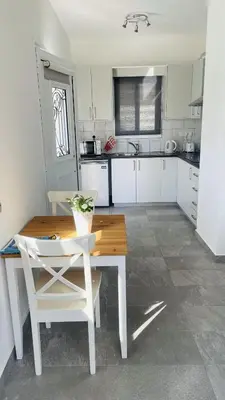 a kitchen with a wooden table and white chairs at Villa Christo in Psematismenos
