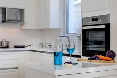 a white kitchen with a glass of blue wine at Accomoteleia Crystal Lagoon Villa in Protaras