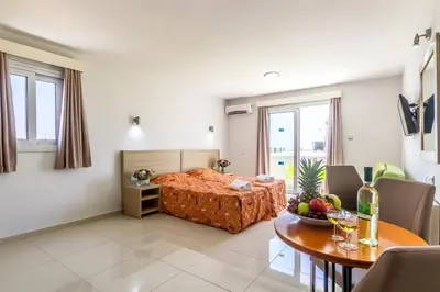 a living room with a bed and a table with a dining room at Paul Marie Hotel Apartments in Ayia Napa