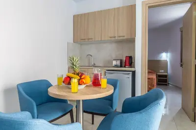 a table with fruit on it in a kitchen with blue chairs at Paul Marie Hotel Apartments in Ayia Napa